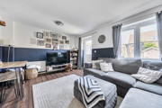 Living room with sofas, tv, windows and a door into back garden.