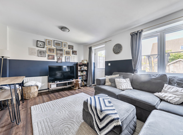 Living room with sofas, tv, windows and a door into back garden.