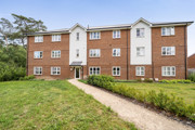 Three-storey brick apartment building with a path leading across a grass lawn.