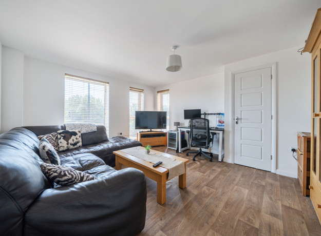 Living and dining area with wood flooring and access to the hallway.