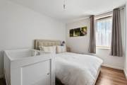 Bedroom with bed, cot, window, and curtains.
