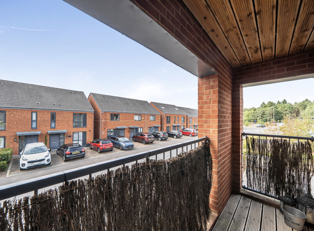Balcony overlooking a residential street with parked cars.