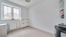 Empty bedroom with window, radiator, dresser and built in shelving.