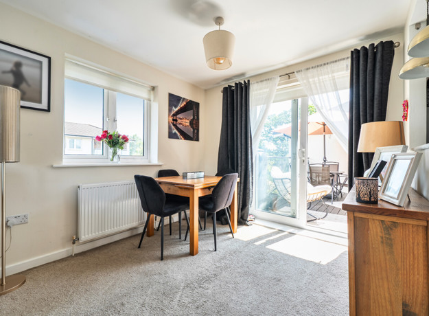 Dining area with a table and chairs beside glass doors to a balcony.