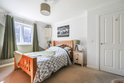 Double bedroom with wooden bed frame, bedside tables, door and window