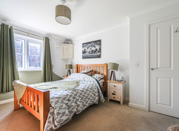 Double bedroom with wooden bed frame, bedside tables, door and window