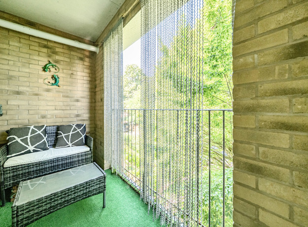Balcony with seating and railings overlooking trees.
