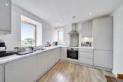 Fitted kitchen with integrated appliances and windows.