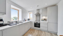 Fitted kitchen with integrated appliances and windows.