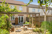 Back garden with patio, pergola, planting beds, and seating area.