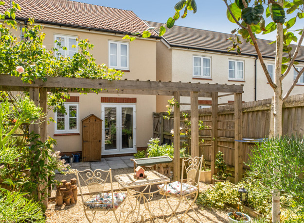 Back garden with patio, pergola, planting beds, and seating area.