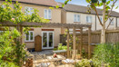 Back garden with patio, pergola, planting beds, and seating area.