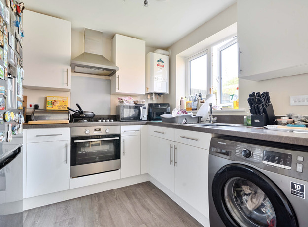 Kitchen with fitted units, appliances, washing machine and window.