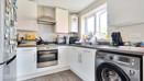 Kitchen with fitted units, appliances, washing machine and window.