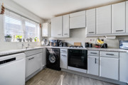 Kitchen with white cabinets, appliances, and window above the sink.