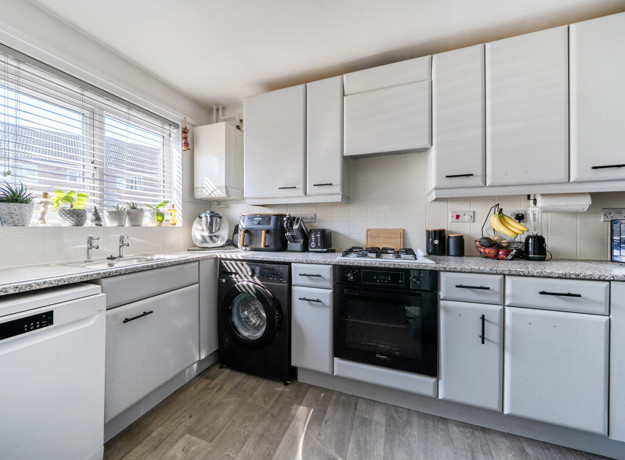 Kitchen with white cabinets, appliances, and window above the sink.