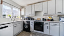 Kitchen with white cabinets, appliances, and window above the sink.