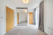Carpeted bedroom with wooden doors, wardrobe with mirrored sliding doors and a ceiling light
