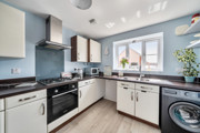 Kitchen with cabinets, oven, washing machine, and window.