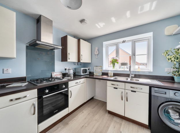 Kitchen with cabinets, oven, washing machine, and window.