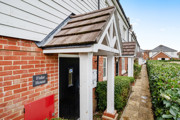 Red brick house entrance with white porch and narrow path along building.