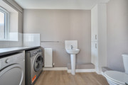 Utility room with washing machine, tumble dryer, toilet and freestanding sink