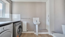 Utility room with washing machine, tumble dryer, toilet and freestanding sink