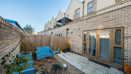 Small patio garden with paving, wooden fence, blue bench, and glass doors.