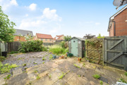 Rear patio area with paving slabs, fencing, shed, and surrounding houses.