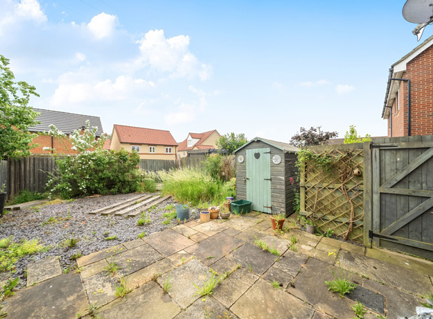 Rear patio area with paving slabs, fencing, shed, and surrounding houses.
