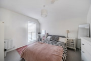 Bedroom with double bed, bedside drawers, and window with white blinds.