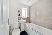 Bathroom with a bathtub, sink, toilet and tiled walls.