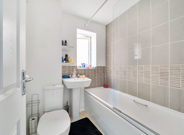 Bathroom with a bathtub, sink, toilet and tiled walls.