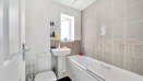Bathroom with a bathtub, sink, toilet and tiled walls.