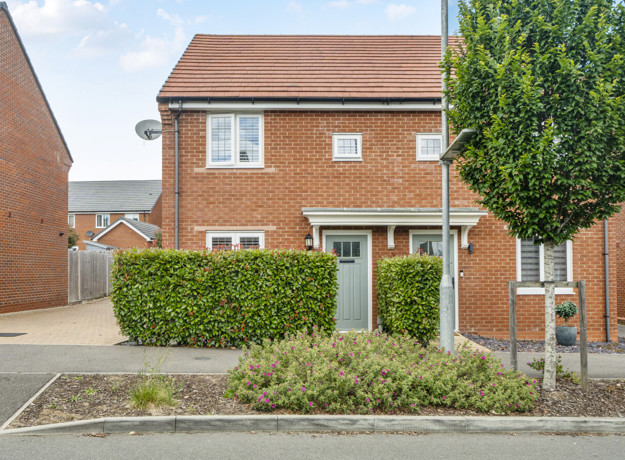 Brick semi-detached house with front lawn, hedge, and driveway.