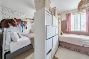 Bedroom with two beds, storage, decorative wall art and a window.