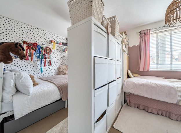 Bedroom with two beds, storage, decorative wall art and a window.