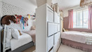 Bedroom with two beds, storage, decorative wall art and a window.