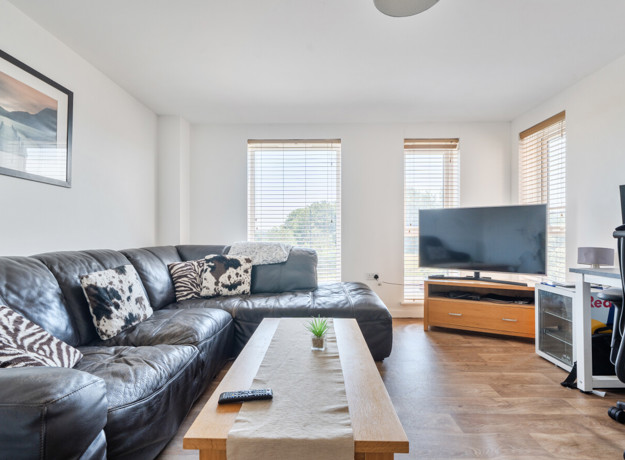 Open-plan living area with sofas, TV and large windows.
