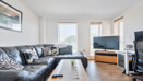 Open-plan living area with sofas, TV and large windows.