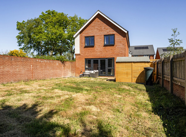 Rear garden with lawn, fenced boundaries and detached house exterior