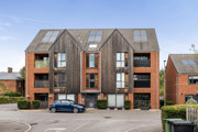 Exterior view of a red brick apartment building with parked cars outside.