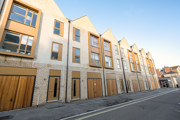 Row of modern townhouses along a clean street with pale brick and large windows.