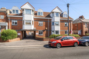 Brick apartment building with balconies and parked cars outside.