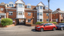 Brick apartment building with balconies and parked cars outside.