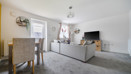 Living room with grey carpet, sofa, TV, dining table and garden doors.