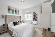 Bedroom with double bed, bedside tables, window and wall-mounted television.