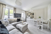 Living room with sofas, TV, storage unit, dining table and large window.