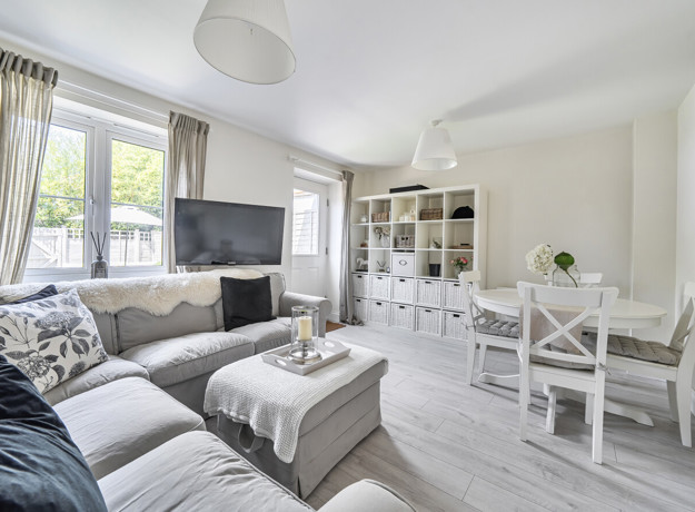 Living room with sofas, TV, storage unit, dining table and large window.