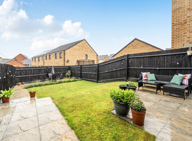 Patio and garden with seating, lawn area and fenced boundaries.